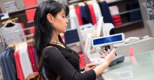 Junge Frau mit langen Haaren bezahlt mit Karte in einem Bekleidungsgeschäft  an der Kasse; Foto aus dem MLR-Faltblatt zu RFID