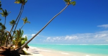 weißer Sandstrand mit Palmen, türkisem Meer und blauem Himmel