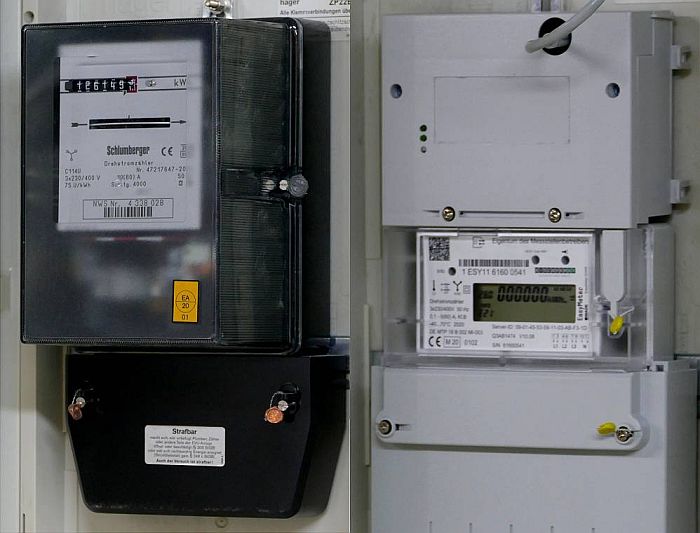 Links hängt ein alter Ferraris-Stromzähler in schwarz an der Wand, daneben hängt ein grauer, digitaler Stromzähler. Links hängt ein alter Ferraris-Stromzähler in schwarz an der Wand, daneben hängt ein grauer, digitaler Stromzähler.