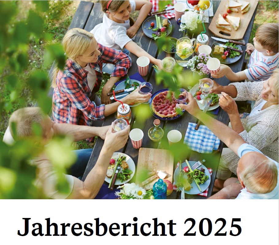 Titelseite des Jahresberichts zur Lebensmittelüberwachung 2025: Reichlich gedeckter Holztisch mit Essen und Menschen beim Picknick