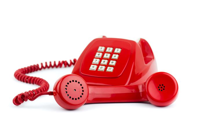 Altertümliches rotes Tastentelefon mit Knochenhörer und weißen Wähltasten und rotem Kabel Altertümliches rotes Tastentelefon mit Knochenhörer und weißen Wähltasten und rotem Kabel