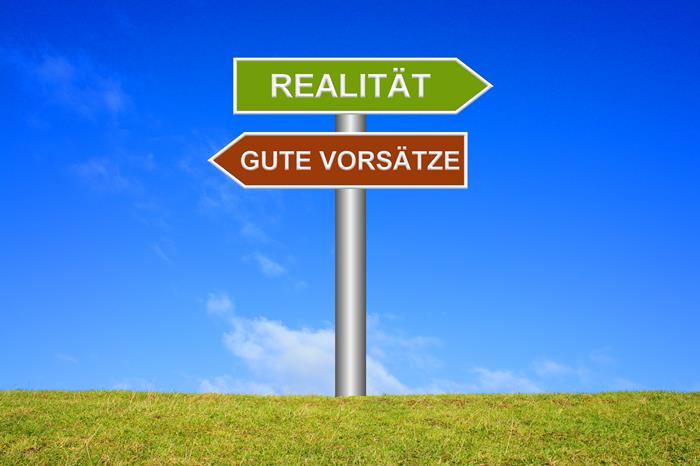 Wegweiser auf grüner Wiese vor blauem Himmel mit grünem Schild nach rechts