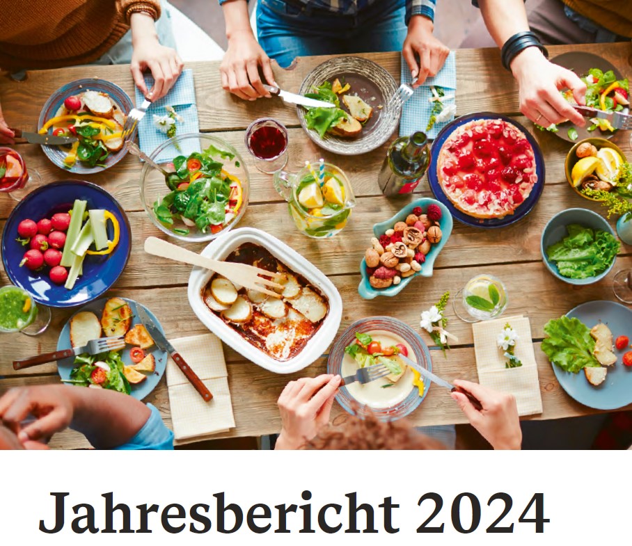 Titelseite des Jahresberichts zur Lebensmittelüberwachung 2024: Reichlich gedeckter Holztisch mit Essen